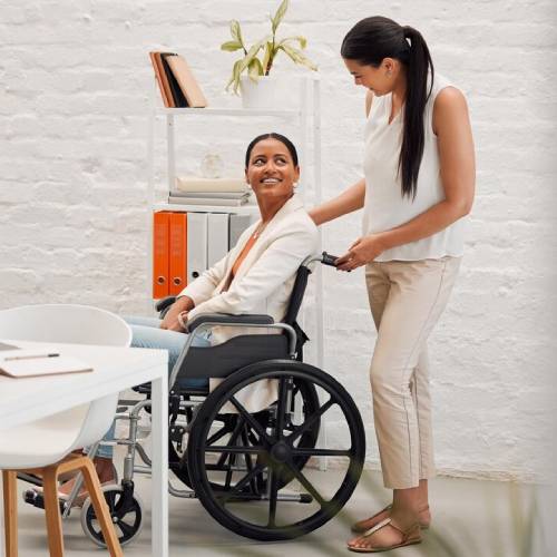 Disability service provider assisting woman in wheelchair at office