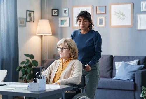 Caregiver assisting woman in wheelchair at home with disability service