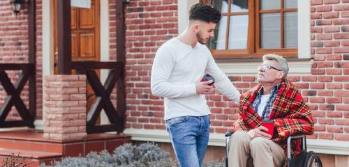 In-home respite care with caregiver supporting elderly man in wheelchair